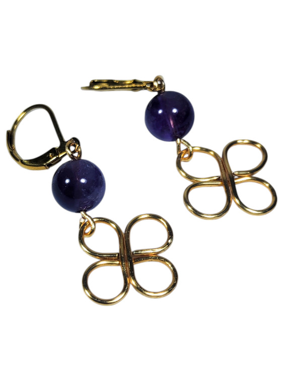 گوشواره دستساز با قفل طلایی، مهره سنگ آمیتیست بنفش براق و آویز فلزی طلایی با فرم گرهای ظریف، روی پسزمینه سفید.